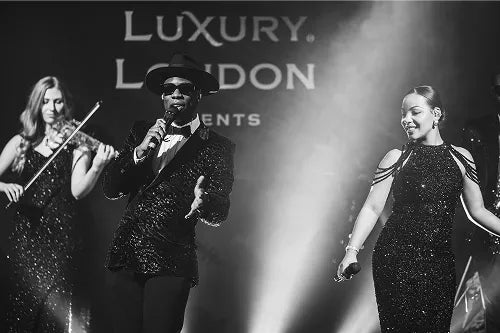 A black and white photograph of a live band and singers performing on stage at the London New Year's Eve Masquerade